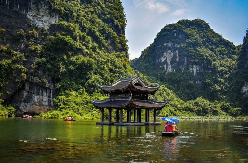 Limestone karst formations at Ha Long Bay near Hanoi with traditional junk-style cruise vessel sailing through the bay at golden hour