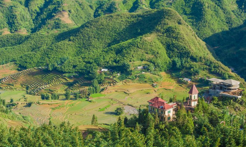 Stone-paved Cat Cat Village trekking trail descending through green Muong Hoa Valley rice terraces with Sapa mountain backdrop