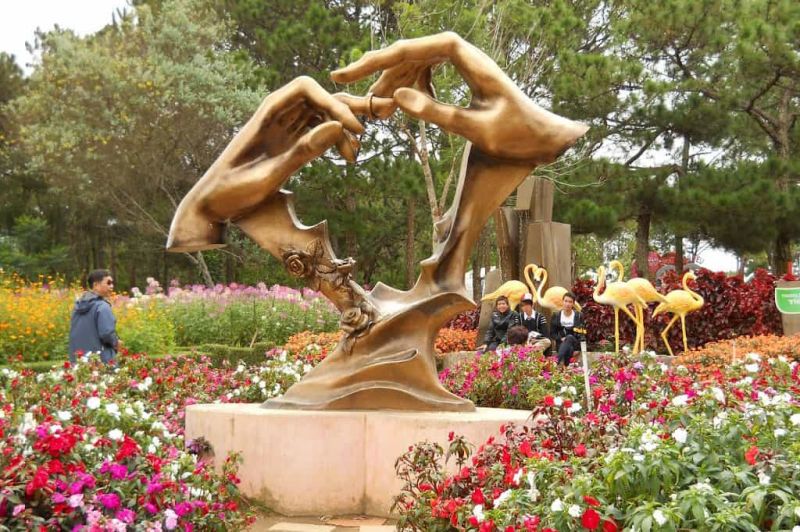 Couple posing for pre-wedding photoshoot among sculpted flower terraces at Dalat Valley of Love during dry-season morning light