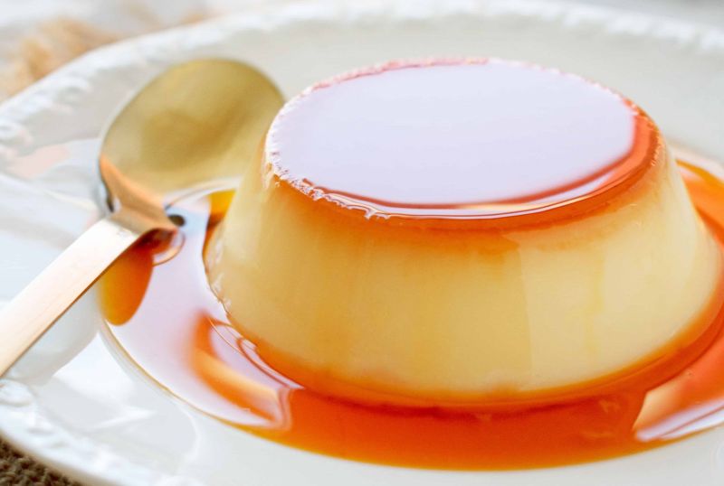 Vietnamese Banh Flan crème caramel on a saucer with caramel sauce and a drip-coffee top, the local adaptation of French crème caramel introduced in the 19th century