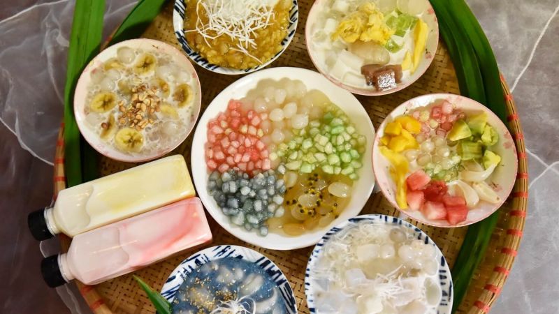 Vietnamese Che sweet soup vendor scooping layered Che varieties into tall glasses at a Hanoi Old Quarter street stall, the most popular dessert in Vietnam category