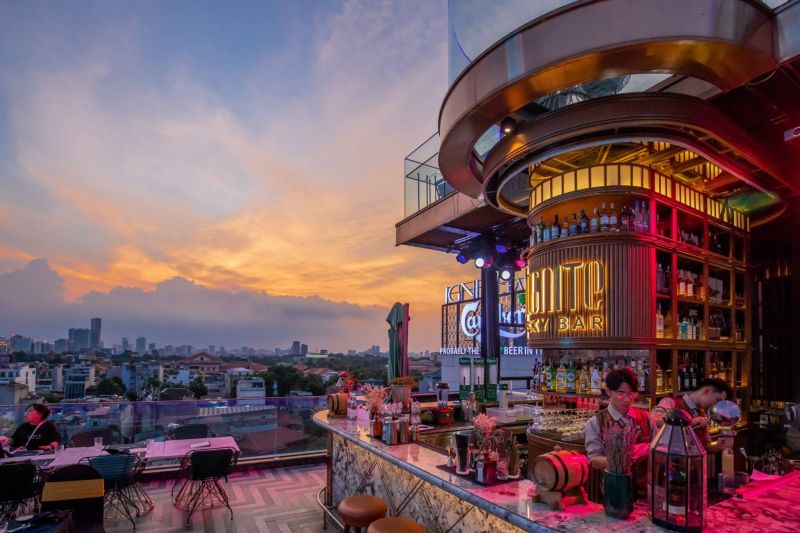 Hanoi rooftop bar with panoramic Hoan Kiem Lake view at night showing cocktails, indoor-outdoor seating, and the illuminated Old Quarter skyline