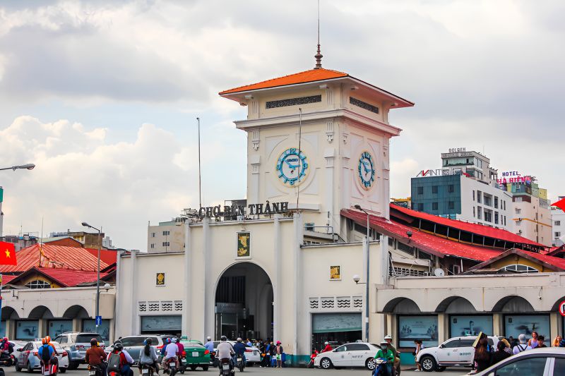 Ben Thanh Market District 1 main entrance archway with vendors and Indian tourists shopping for souvenirs