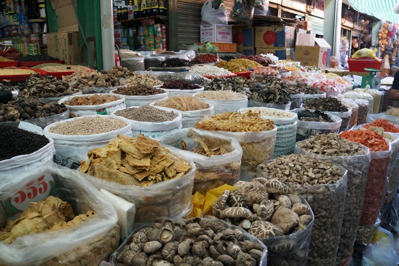 Dried Vietnamese spices star anise cinnamon sticks and Phu Quoc black pepper in baskets at Ben Thanh Market spice section