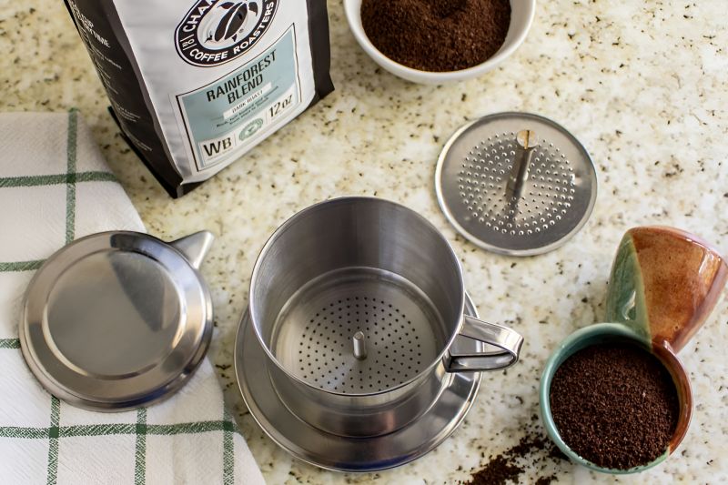 Vietnamese ground coffee packs and stainless steel phin filter set arranged for sale at Ben Thanh Market