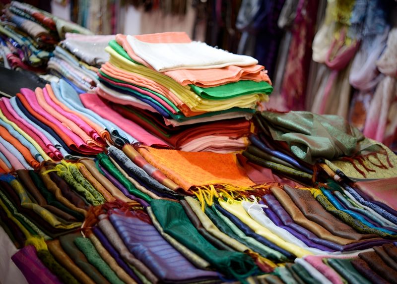 Vietnamese silk scarves in pastel colors hanging at a Ben Thanh Market inner stall display