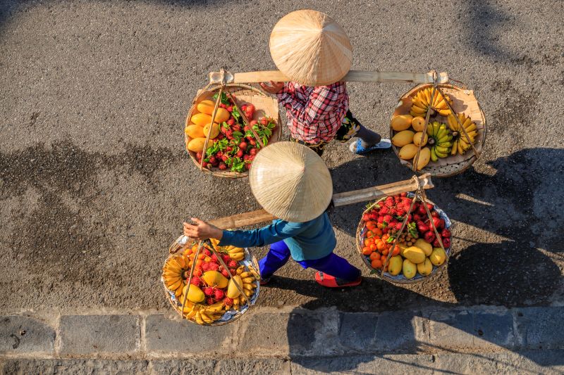 Best time to visit Hoi An Night Market shown by Vietnamese women selling tropical fruits in the dry season