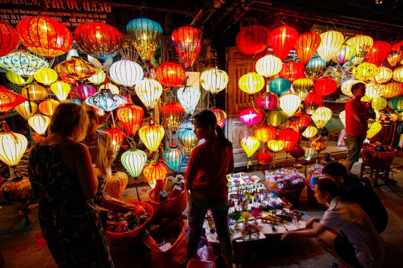 Haggling at Hoi An Night Market between vendor and tourist using Vietnamese phrase Re hon khong