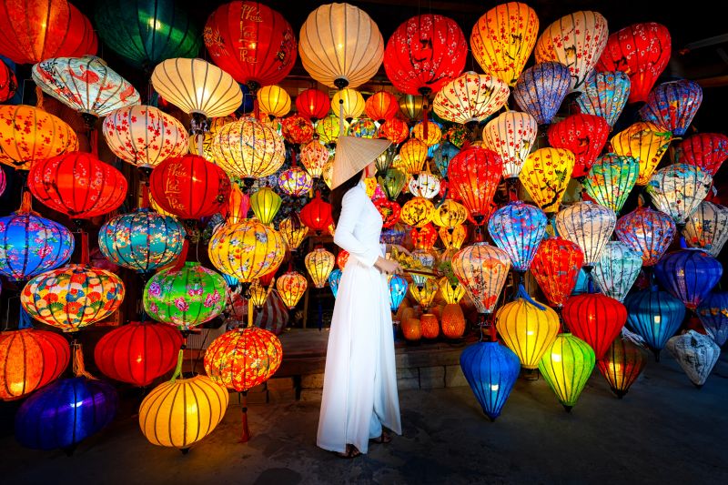 Hoi An Night Market opening hours scene with tourists in Vietnamese traditional clothing and paper lanterns