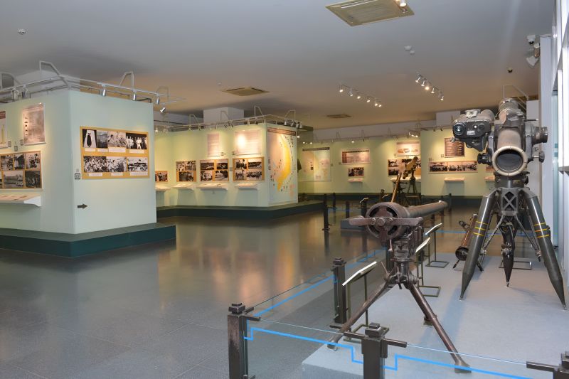 Indian tourists walking through War Remnants Museum exhibition hall reading photograph captions