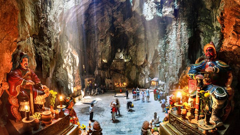 Huyen Khong Cave interior with natural circular skylight illuminating Buddha statue altar Marble Mountains Da Nang