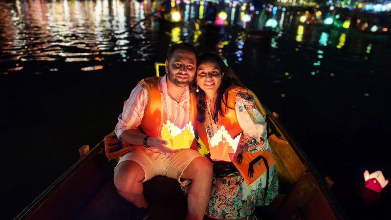 Indian couple releasing lanterns on Thu Bon River boat at Hoi An festival