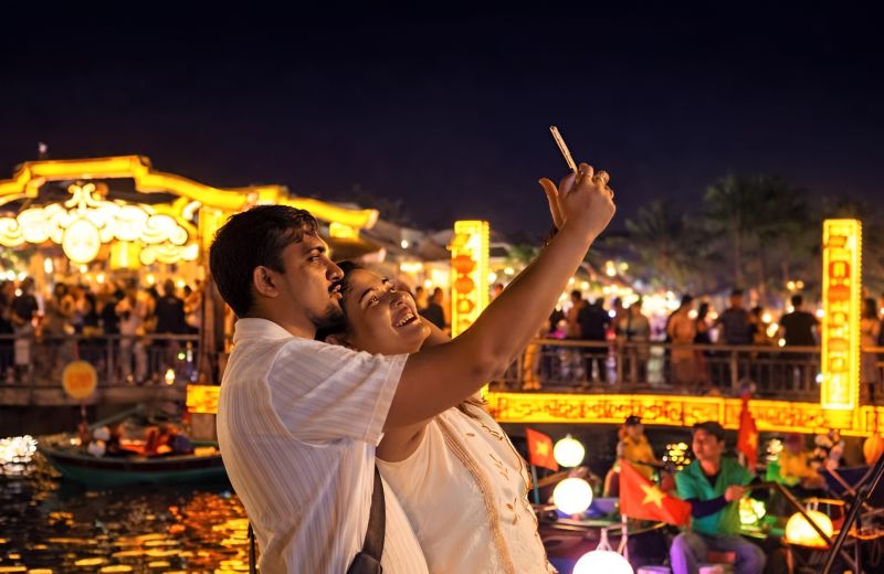 Indian tourists photographing Hoi An Lantern Festival at Bach Dang Riverside