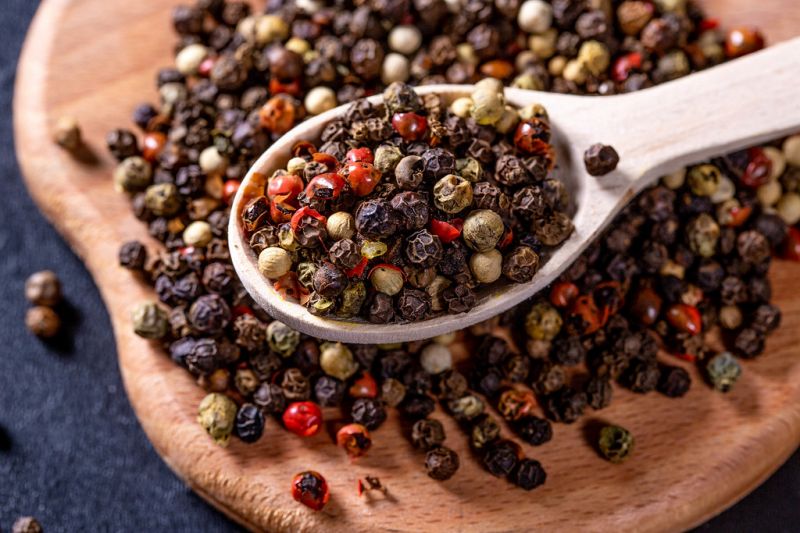 Phu Quoc red pepper compared side by side with Kerala black pepper showing color and grain difference