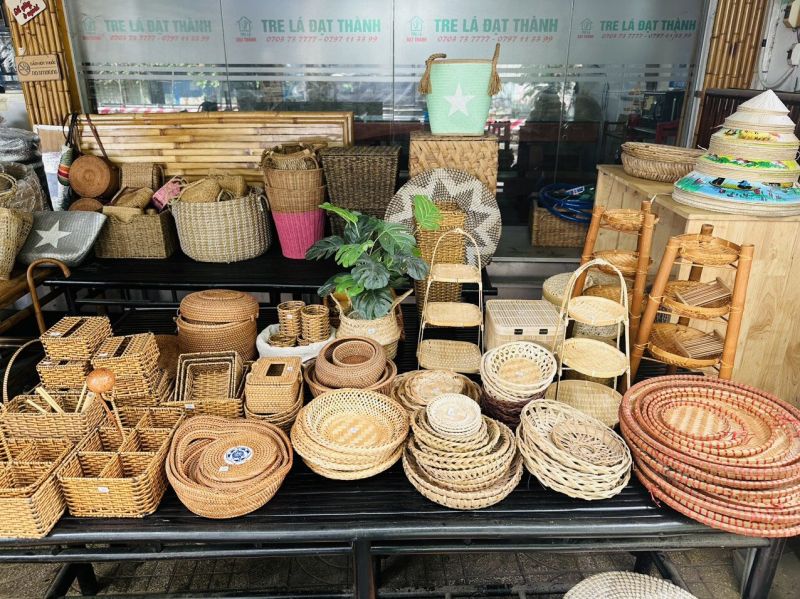 Rattan baskets trays and woven bamboo plates in multiple sizes and weave patterns displayed on black metal table at Tre La Dat Thanh shop
