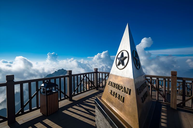 Fansipan summit monument at 3143 metres with star emblem against blue sky and white clouds above the mountain range