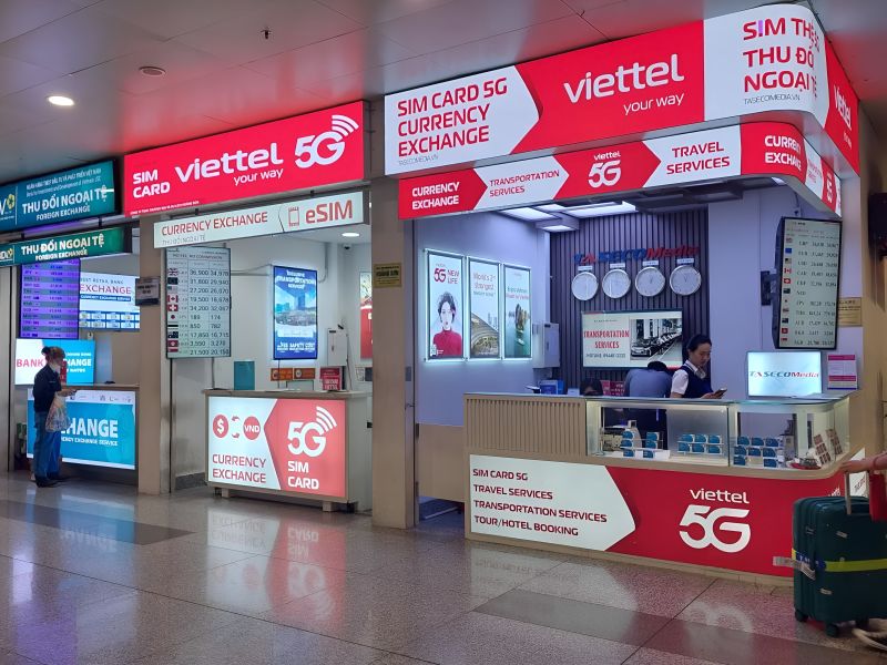 Viettel 5G SIM card counter and eSIM booth alongside currency exchange kiosks in Noi Bai Airport Terminal 2 arrival hall