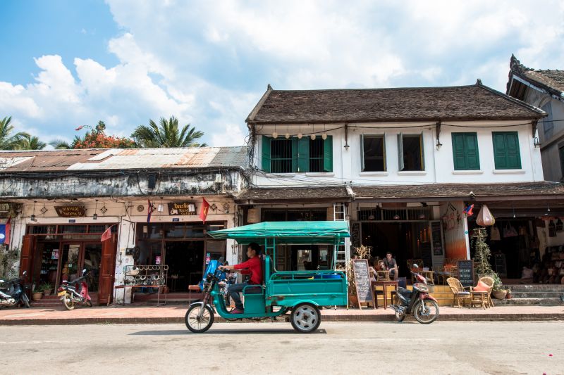 Daytime street view of Sisavangvong Road in Luang Prabang Laos with restaurants tuk tuks and tourists during the dry season
