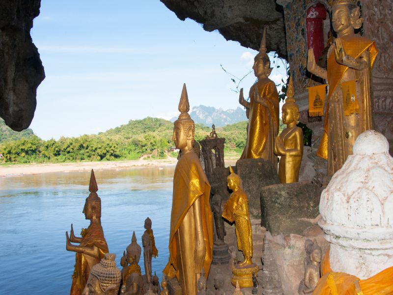 Interior view of Pak Ou Caves in Laos with hundreds of small Buddha statues stacked along the cave walls above the Mekong River