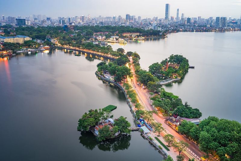 Tran Quoc Pagoda's 11-storey red-brown brick tower reflected in West Lake at dusk in Tay Ho District, Hanoi